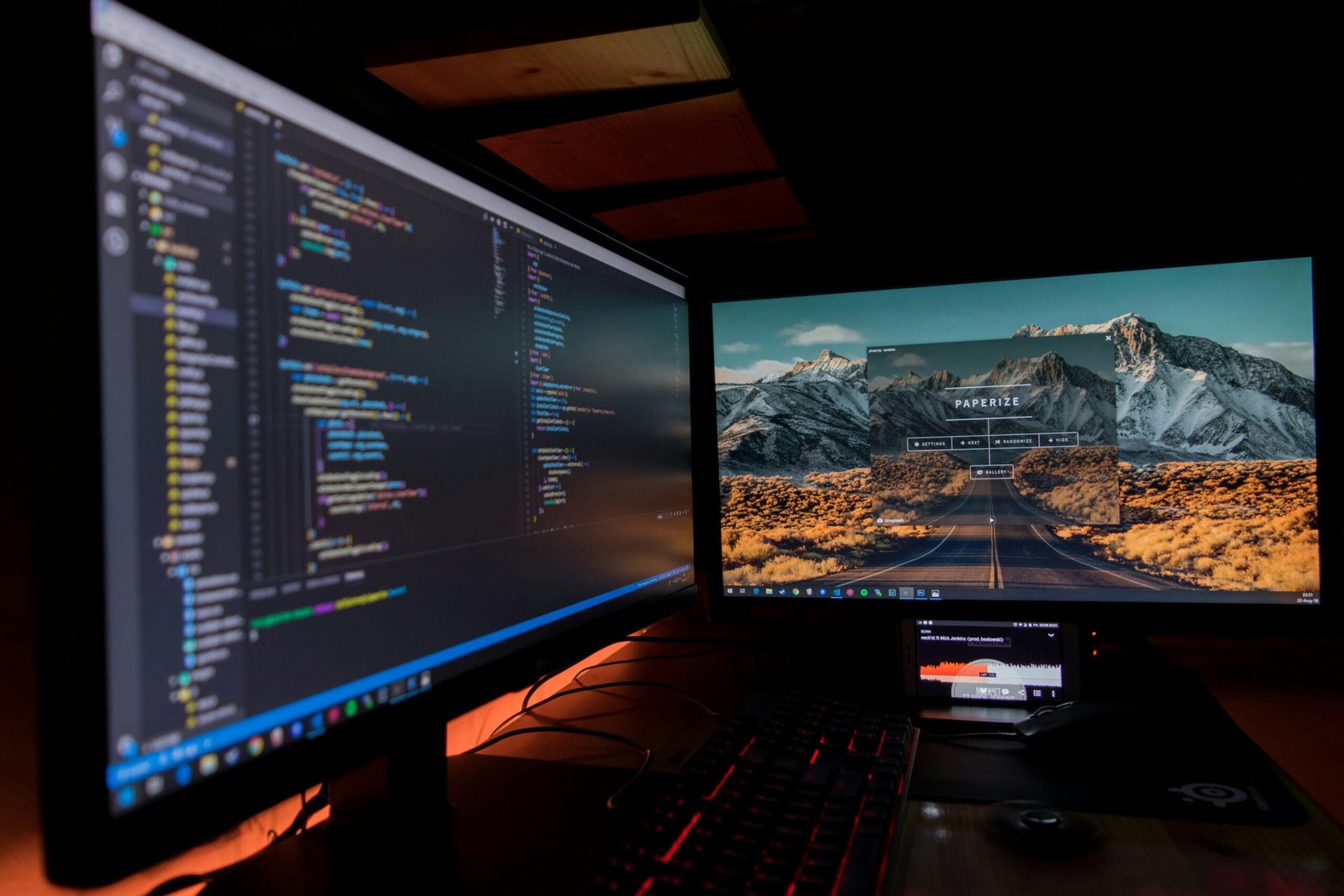 A home workspace with two monitors, keyboard and speakers